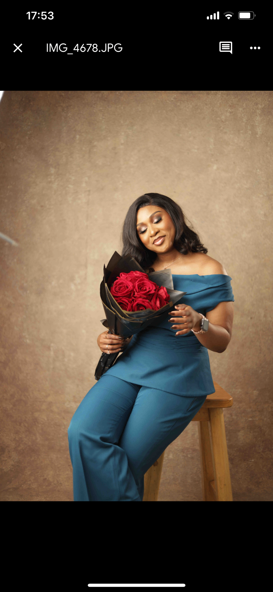 Nneoma in teal outfit holding red roses